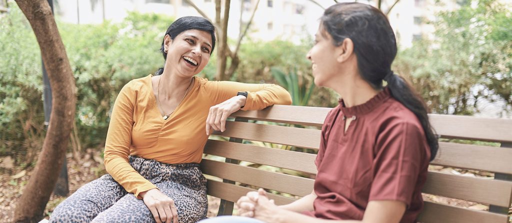 Two women talking on a bench in a park