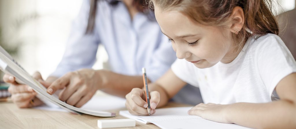 Young girl being guided to fill out a sheet of paper